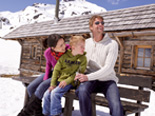 Familie vor einer schneebedeckten Hütte